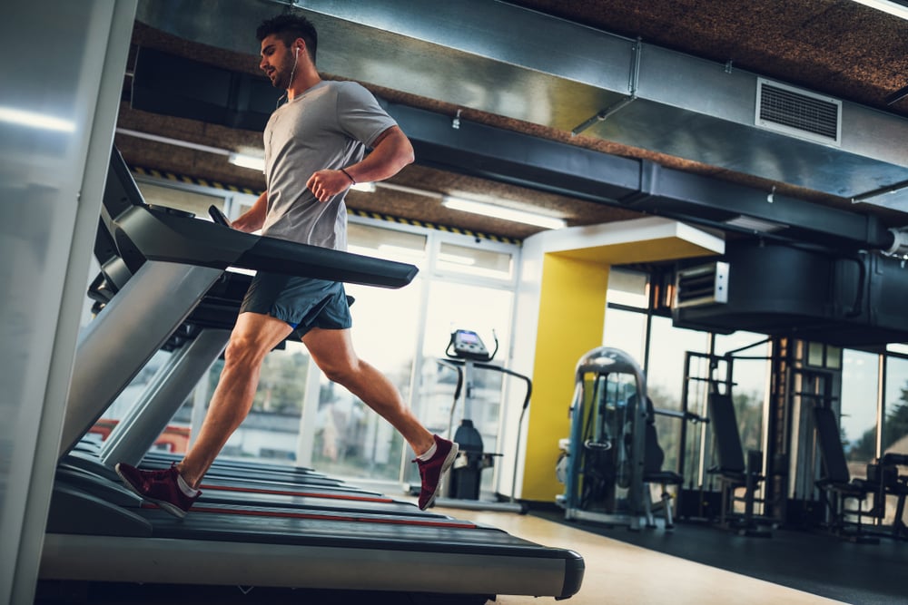 Man running on a treadmill in a gym setting, emphasizing fitness and exercise equipment maintenance relevant to treadmill repair services.