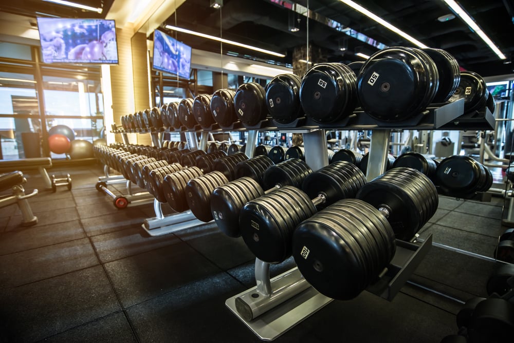 Dumbbells arranged on a rack in a modern gym setting, showcasing fitness equipment essential for strength training and maintenance services.