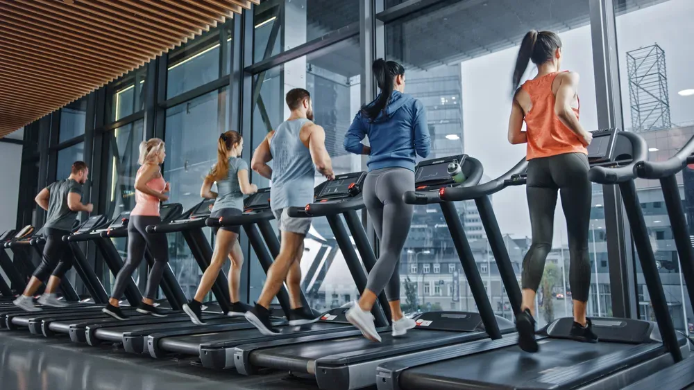 People running on treadmills in a gym, indicating treadmill maintenance and repair needs.