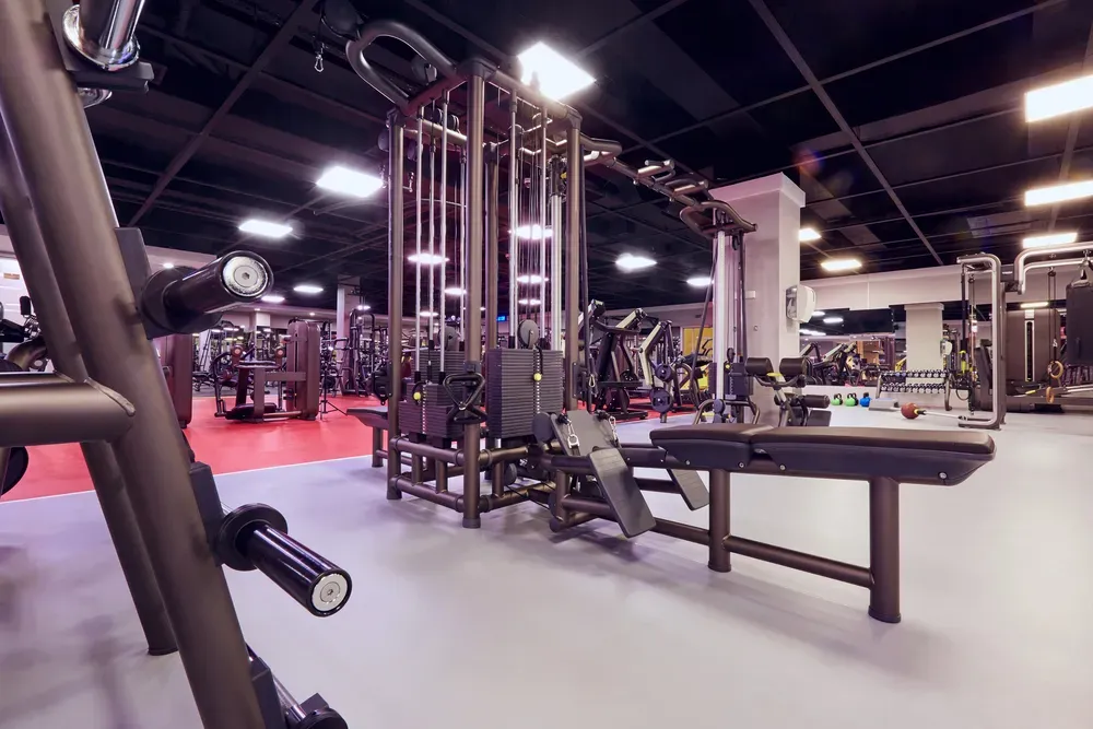 Technician performing scheduled maintenance on fitness equipment in a gym